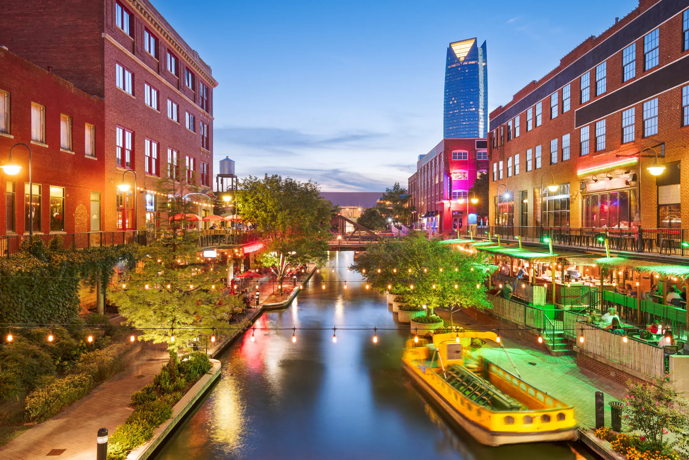 The Bricktown canal at dusk, water taxi passing the patios