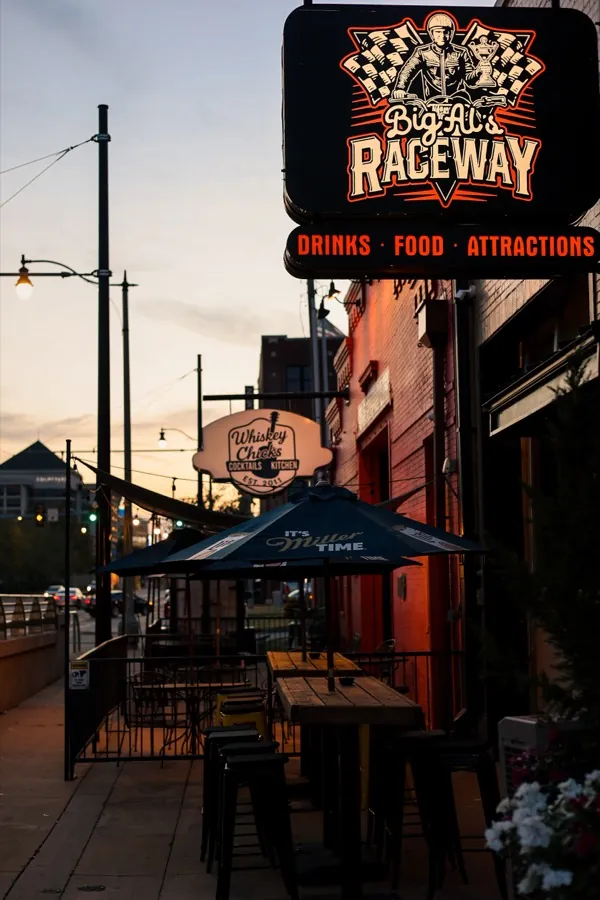 The lit Big Al's Raceway sign — drinks, food, attractions — over the patio on Reno Ave at dusk