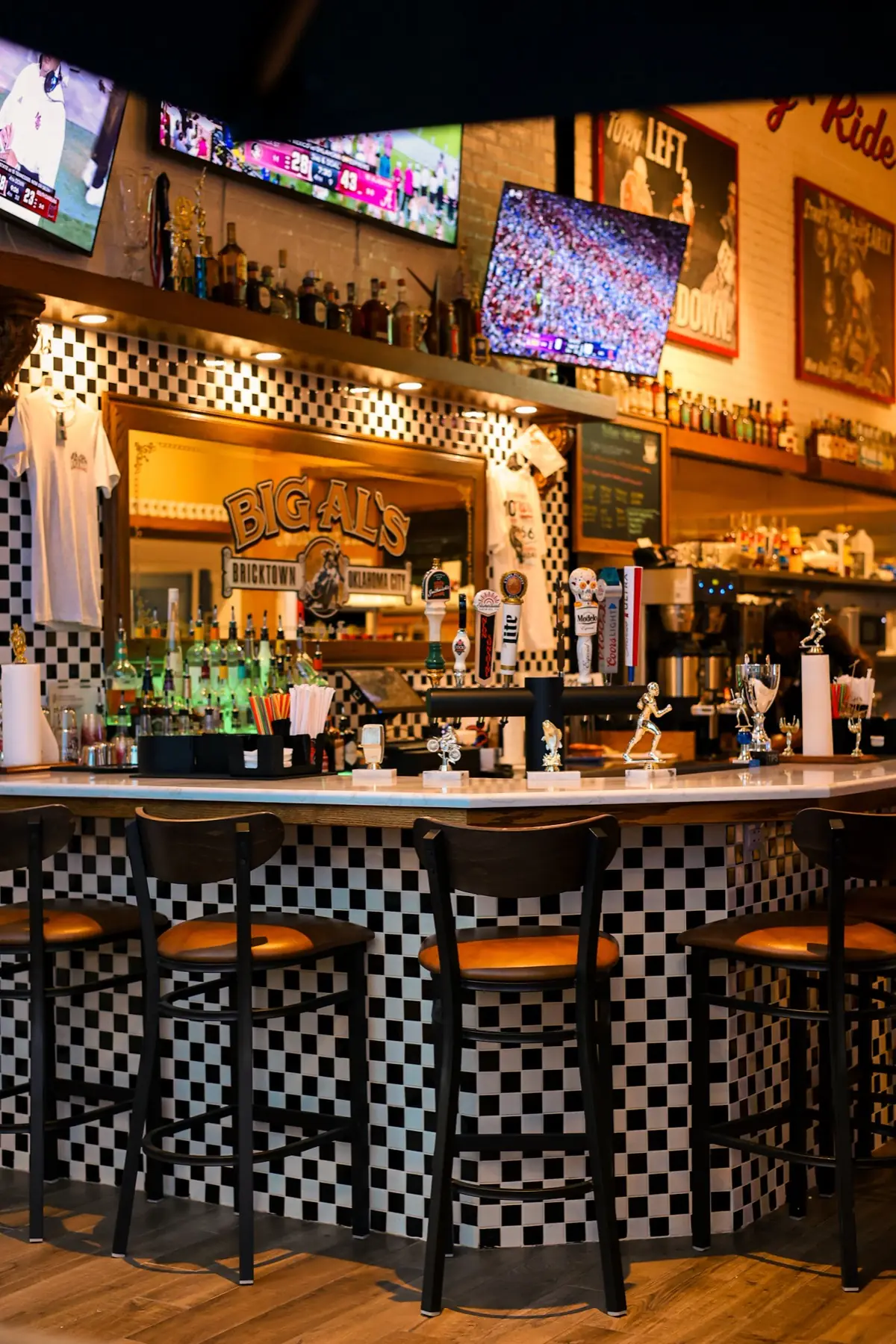 The checkerboard bar at Big Al's — stools along the counter, beer taps and trophies, the Big Al's mirror behind