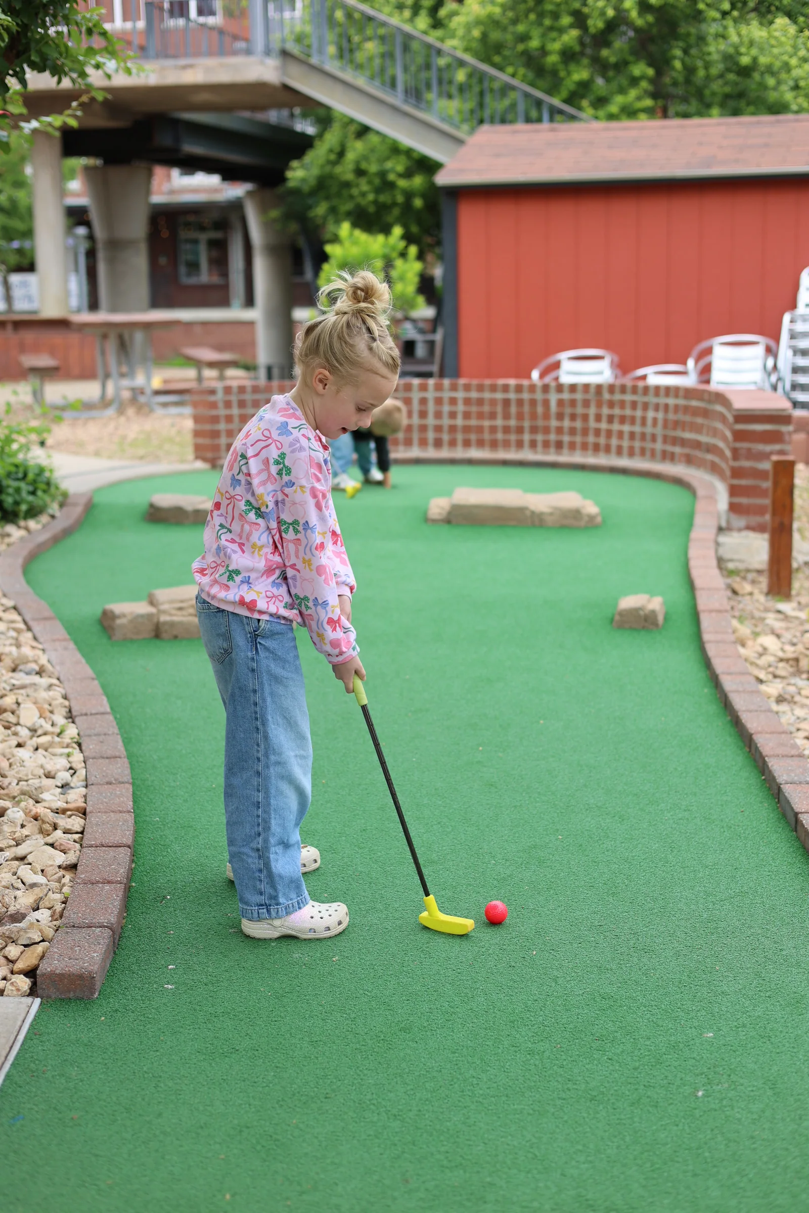 A child lining up a putt on the mini golf course